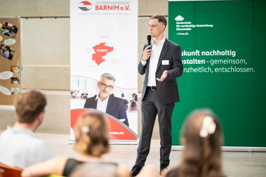 Speaker with a microphone addressing an audience at an event on working-time models