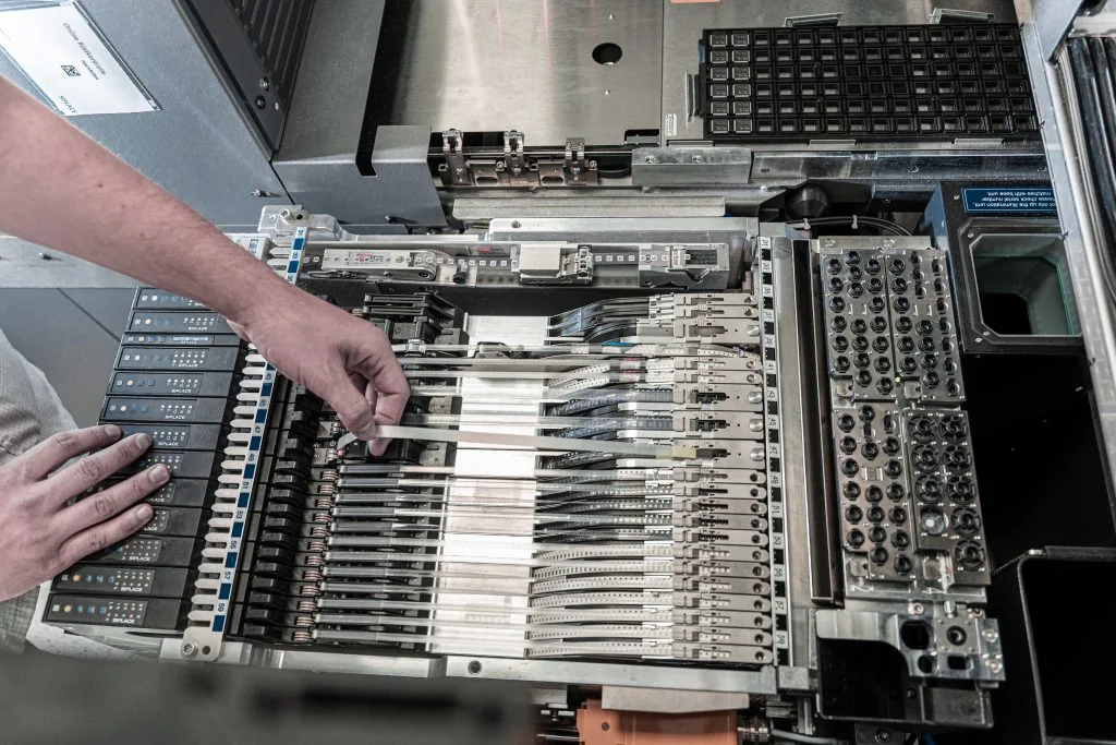 Pracownik załadowuje wózek z podajnikami komponentów do produkcji SMT
