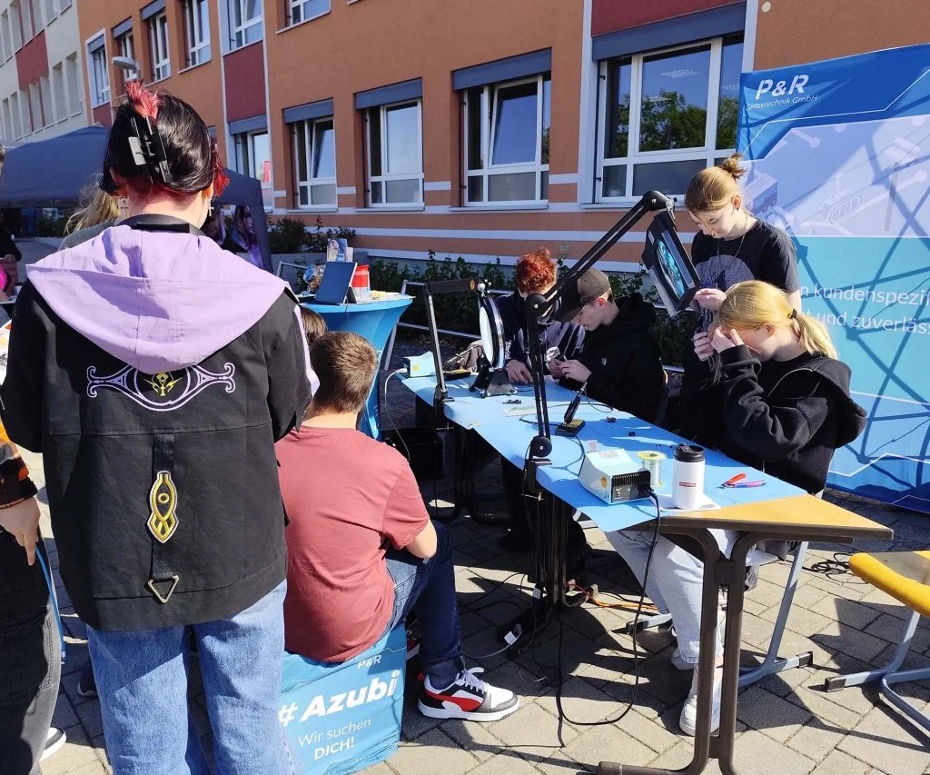 Odwiedzający testują elektronikę na stoisku P&R podczas targów zawodowych