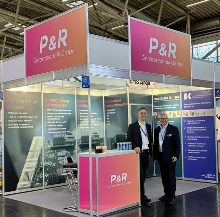 P&R exhibition stand at productronica 2025 with two representatives
